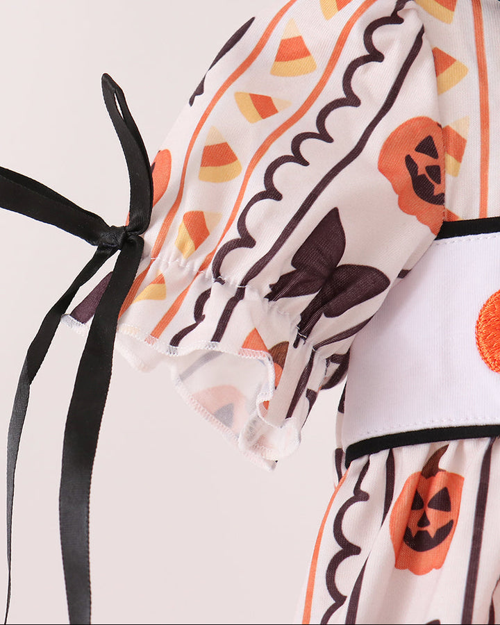 White baby romper sleeve with black bow tie accents and orange pumpkin patterned ruffle trim