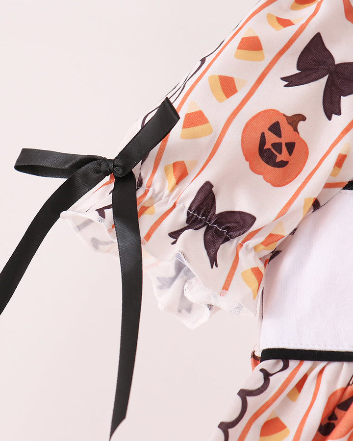 Ruffle dress with long black ribbon bow ties and orange pumpkin-and-bat print sleeves
