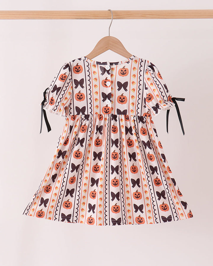 Kids pumpkin ruffle dress with striped fabric, black ribbon ties, and orange pumpkin embroidery