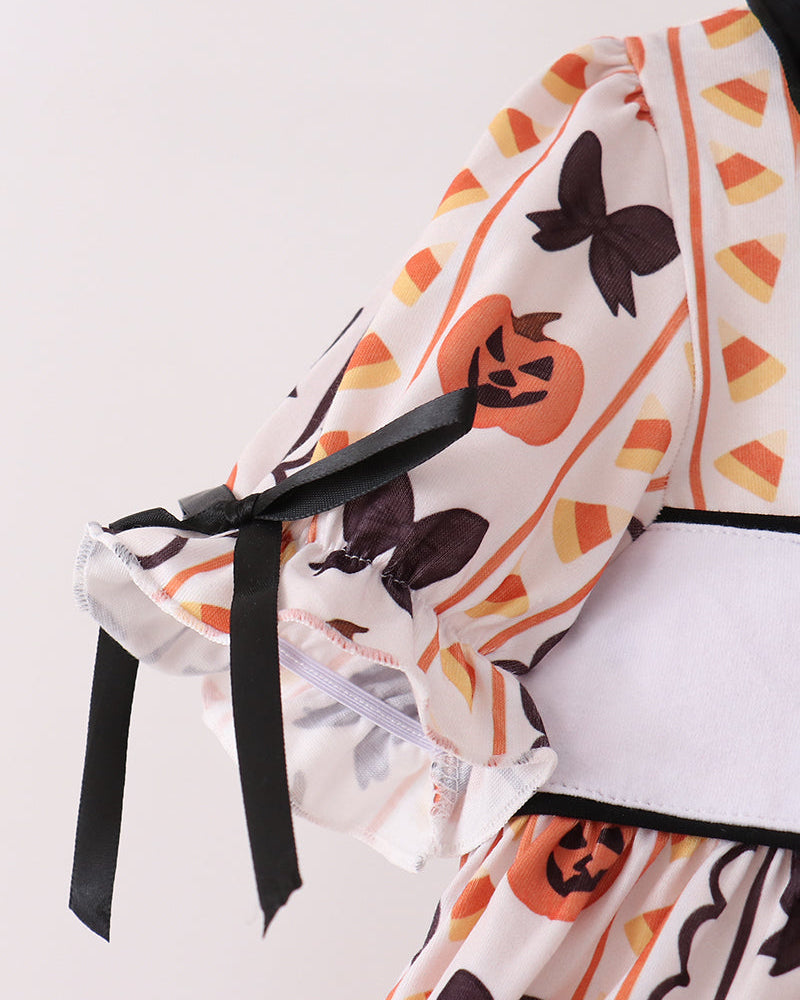 White ruffle top with orange pumpkin and black bat print, tied shoulder bows, and black trim