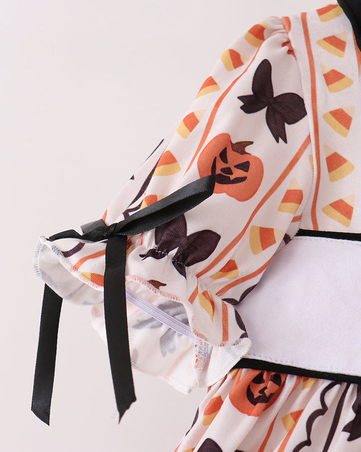 White ruffle top with orange pumpkin and black bat print, tied shoulder bows, and black trim