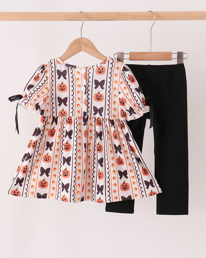 Girl’s ruffle dress with pumpkin-and-bat print and black leggings set, hanging on hangers