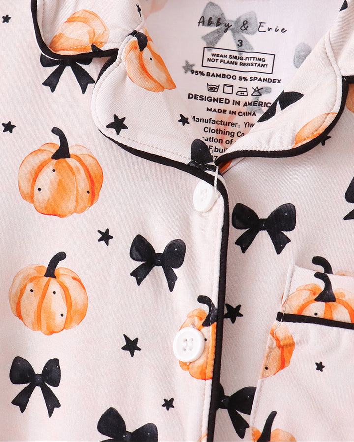 Kids pajama button-up top with pumpkin print, black bow accents, and contrasting trim.
