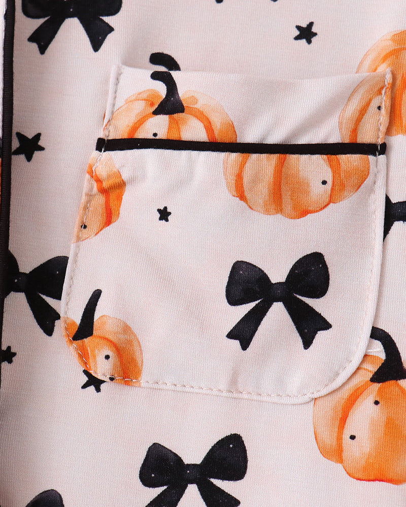 Kids pajama top with front chest pocket, orange pumpkin print, and black bow details.