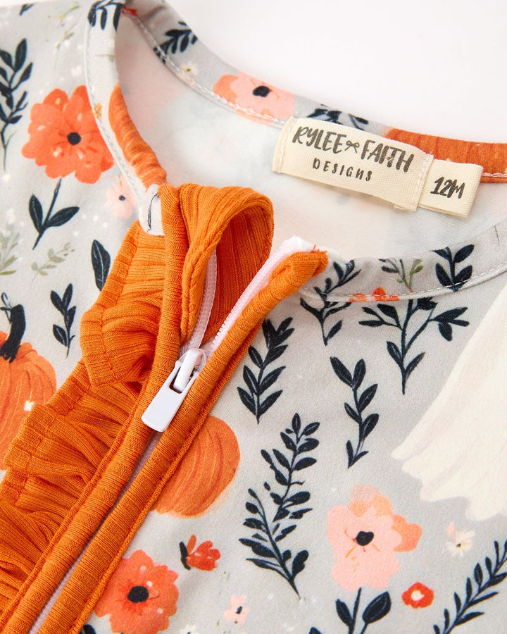 Baby zip romper detail: orange ruffled placket, floral fabric, and size tag on chest