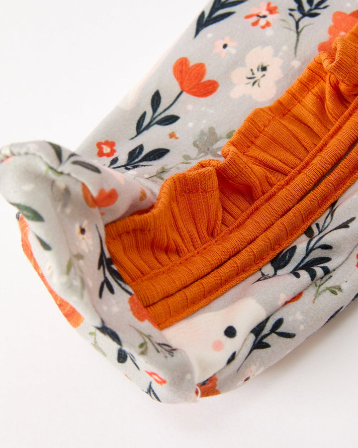 Baby romper sleeve cuff detail with orange ribbed trim on floral printed fabric