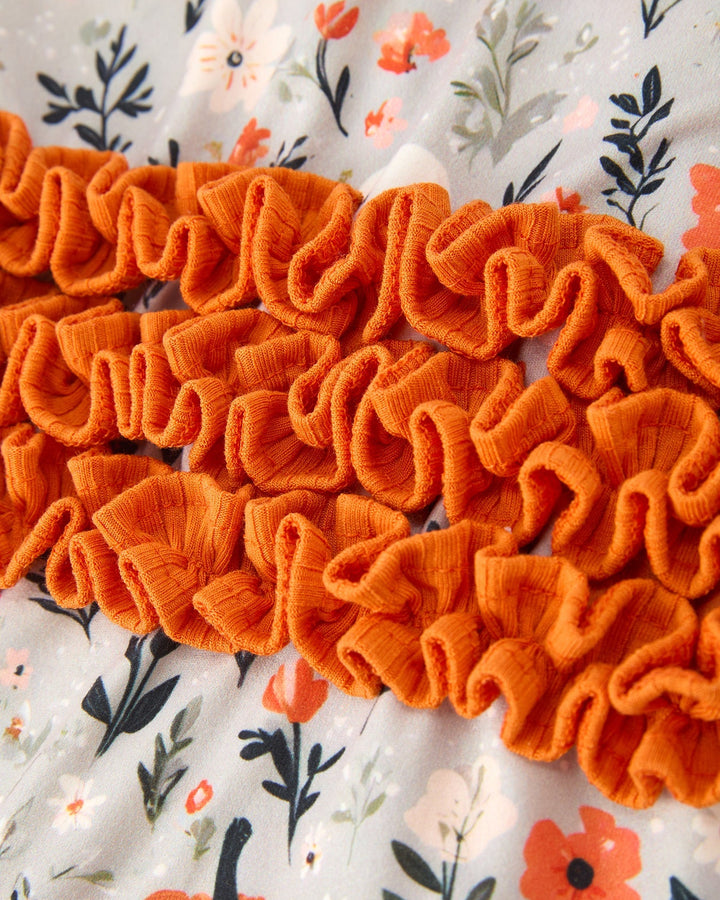 Orange ruffled waistband detail on baby zip romper with floral and pumpkin print