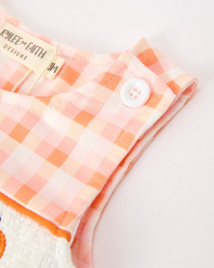 Plaid jonJon sleeve close-up with white snap button and orange stitched edge