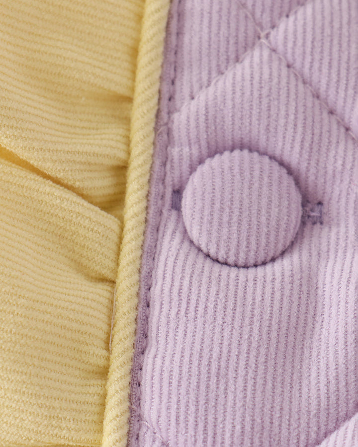 Close-up of yellow-trimmed lavender front with round button and stitched quilt lines