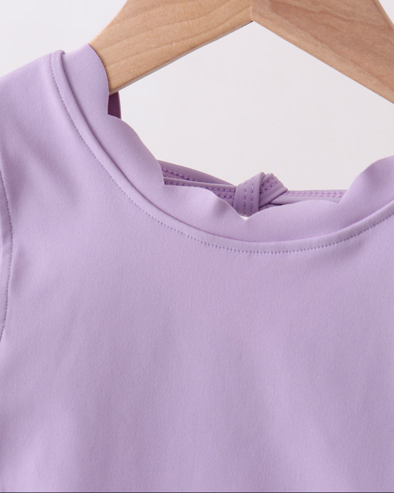 Purple top on a wooden hanger against a white background