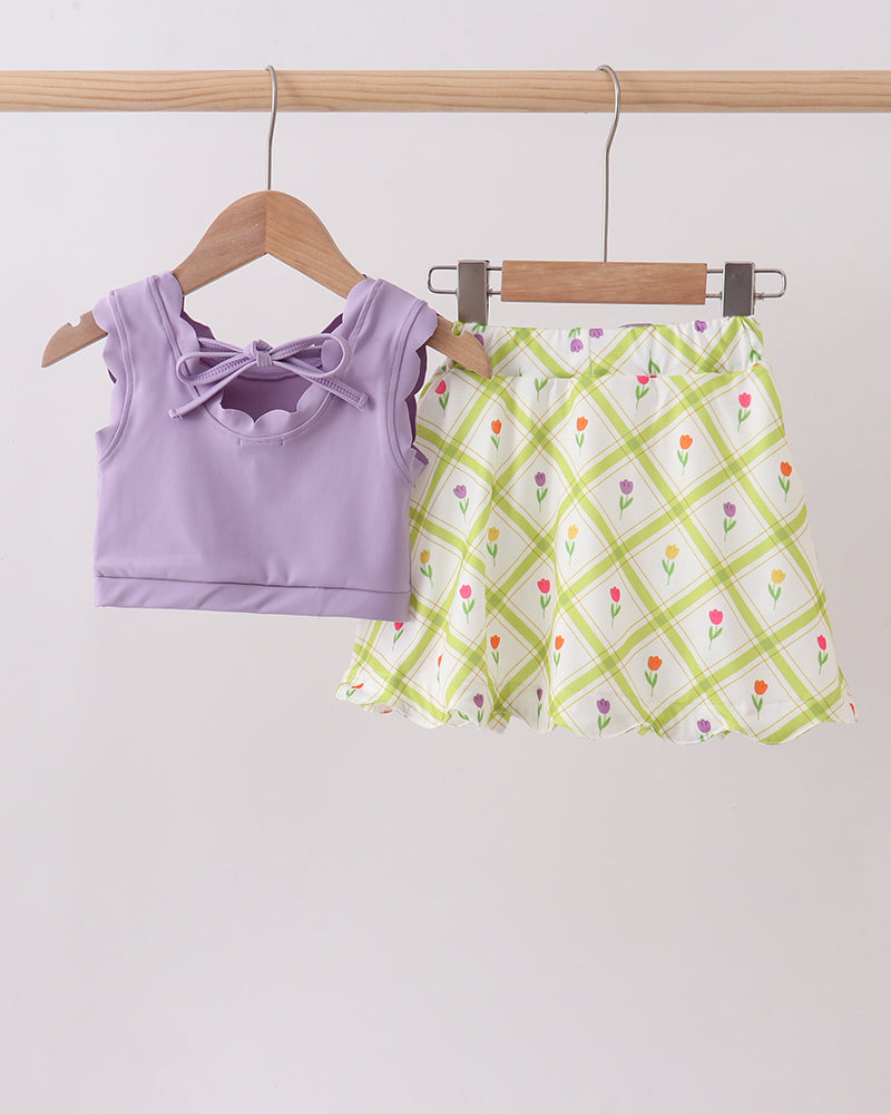 Purple top and floral skirt on hangers against a white background