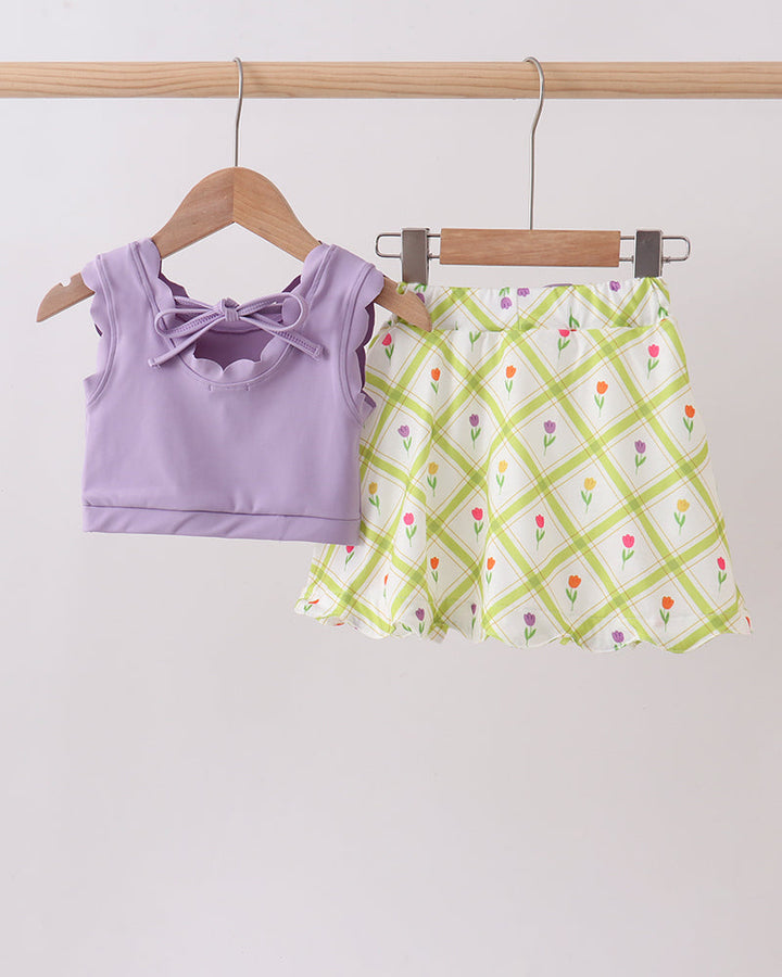 Purple top and floral skirt on hangers against a white background