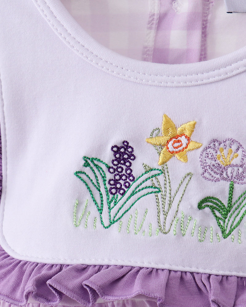 Close up of top with embroidered flowers and purple ruffle