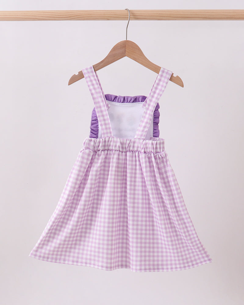 Purple checkered dress on a hanger against a white background