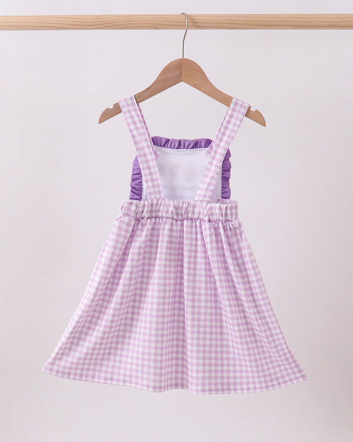 Purple checkered dress on a hanger against a white background