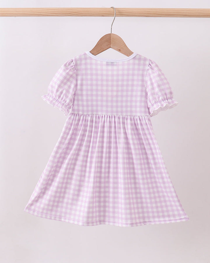 Pink and white checkered dress on a hanger against a white background