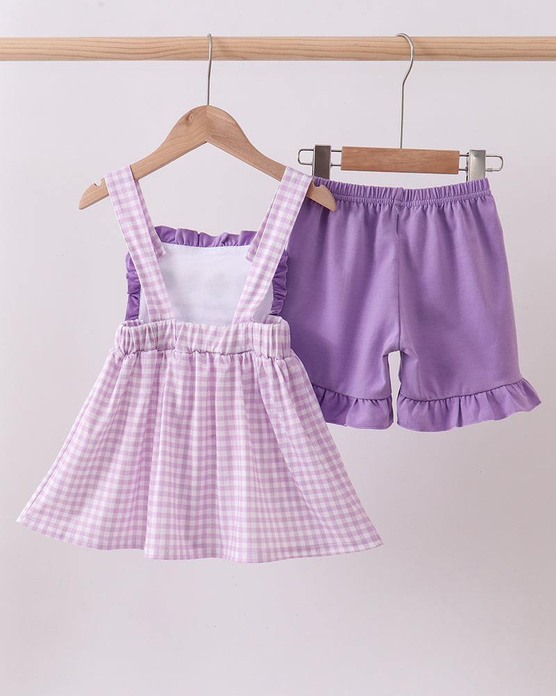 Purple checkered dress and shorts set on hangers against a white background
