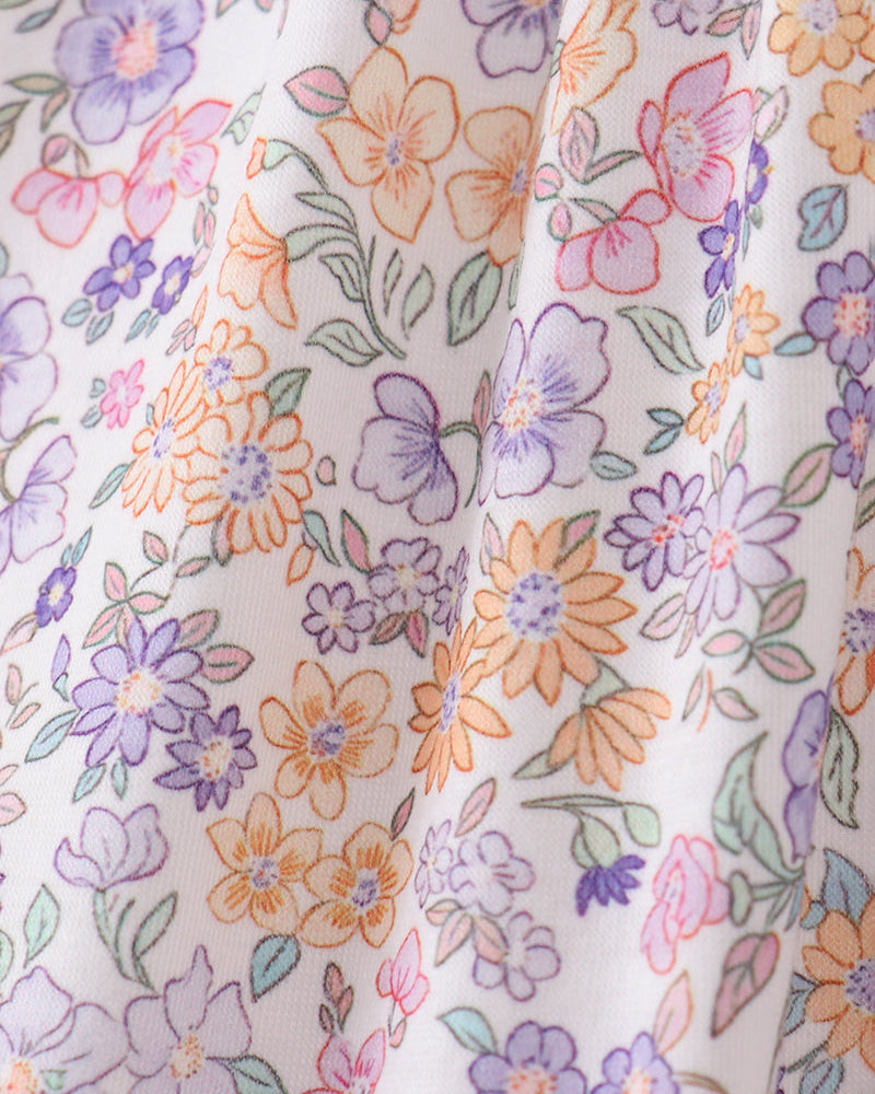 Close-up of fabric with a floral pattern featuring purple, orange, and pink flowers on a white background.