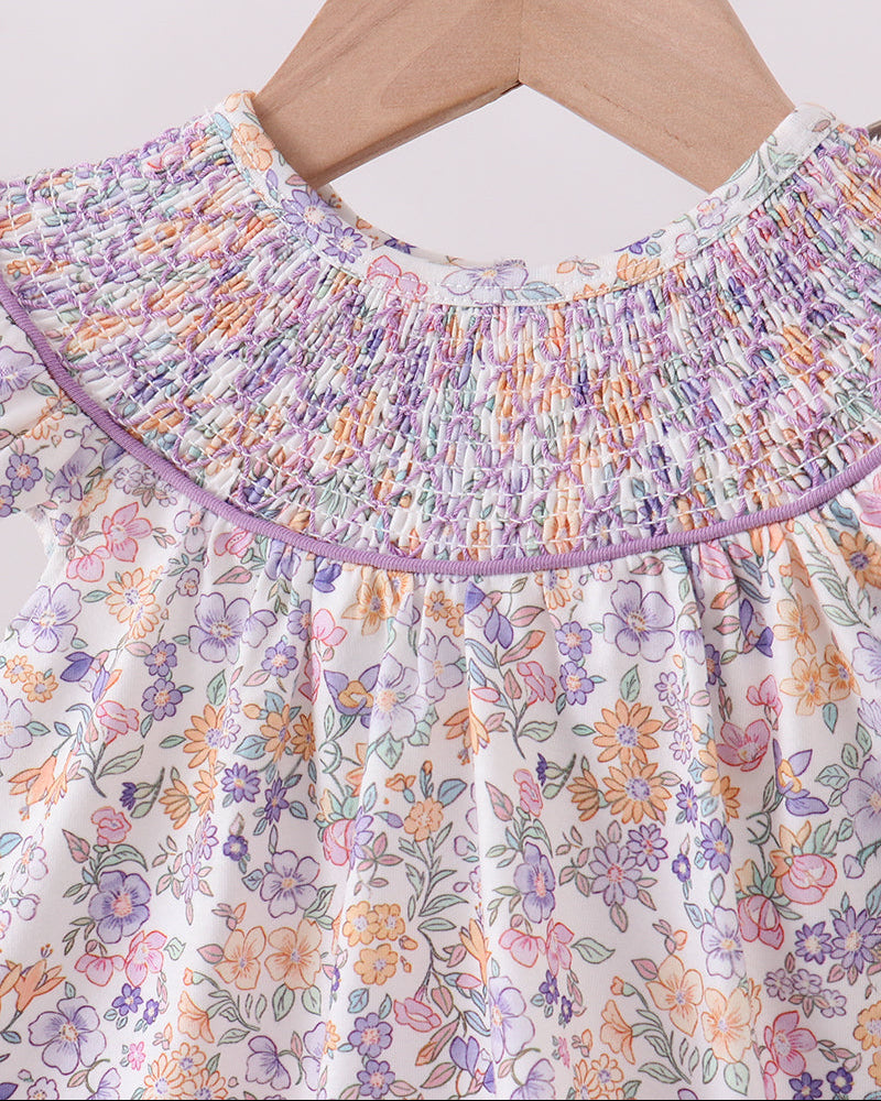 Floral dress with a ruffled neckline on a hanger against a white background