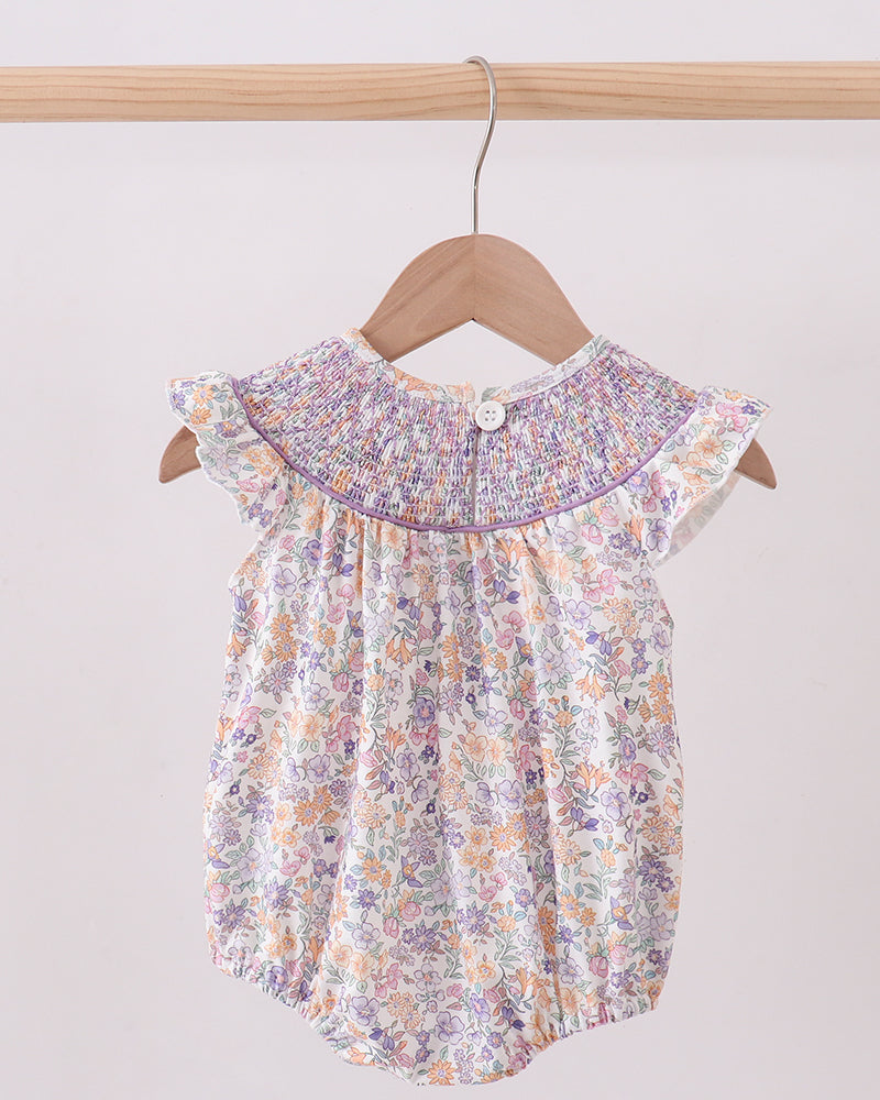 Floral baby romper on a hanger against a plain background