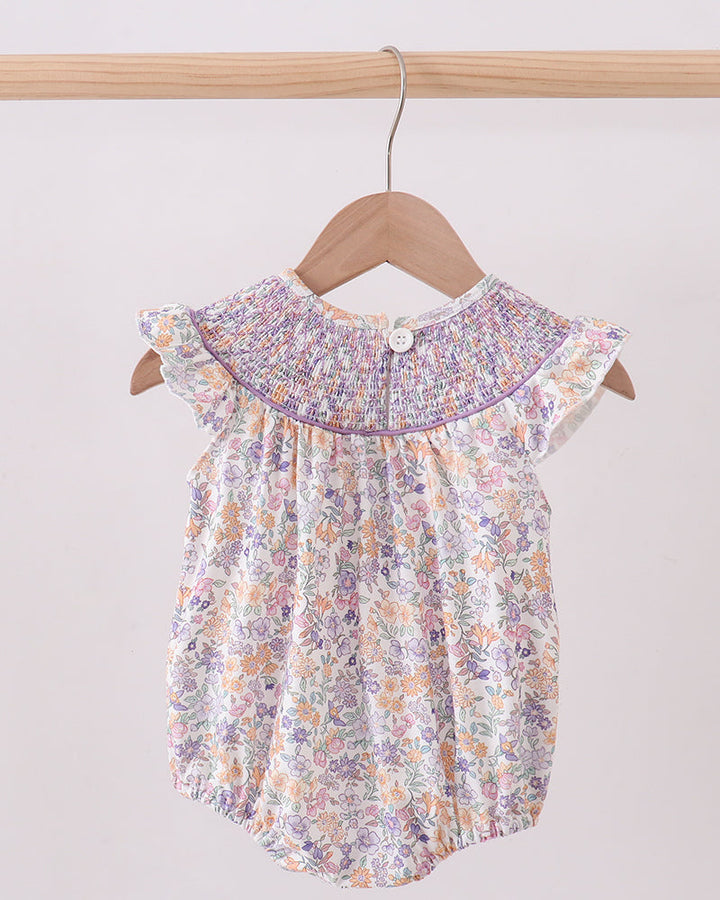 Floral baby romper on a hanger against a plain background