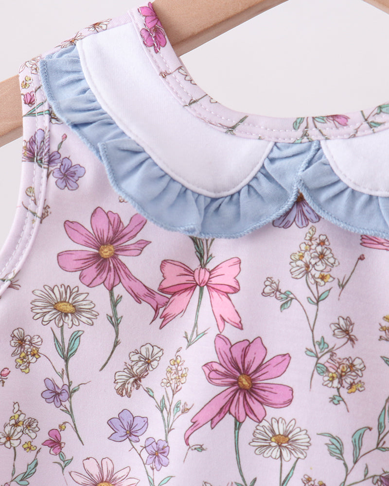 Close-up of a floral-patterned dress with ruffled collar and sleeves.