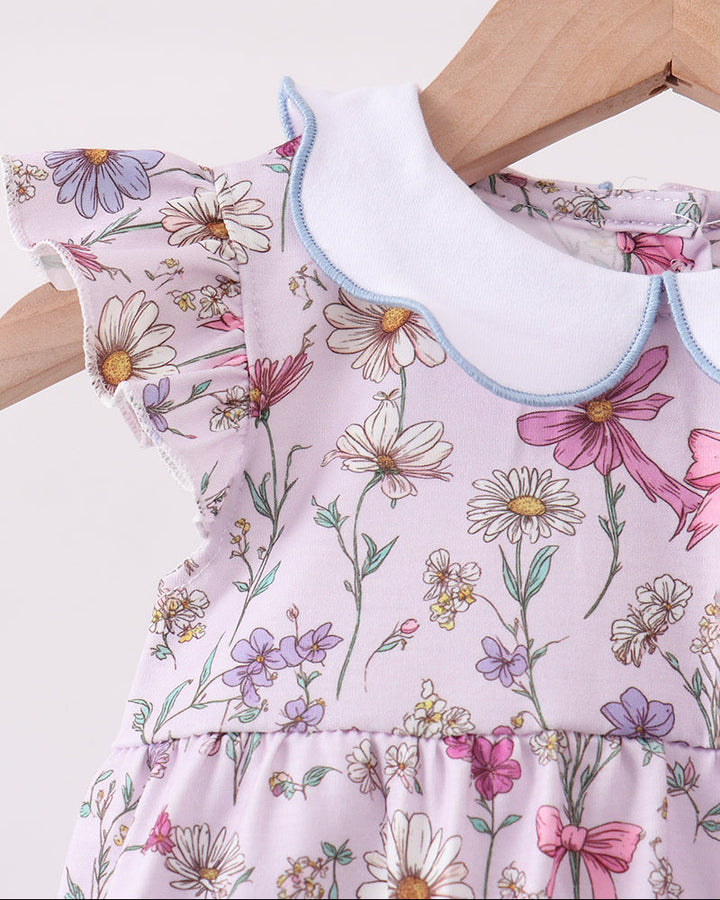 Romper with floral pattern on a hanger against a white background