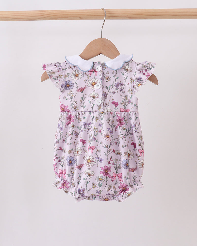Floral baby romper on a hanger against a white background