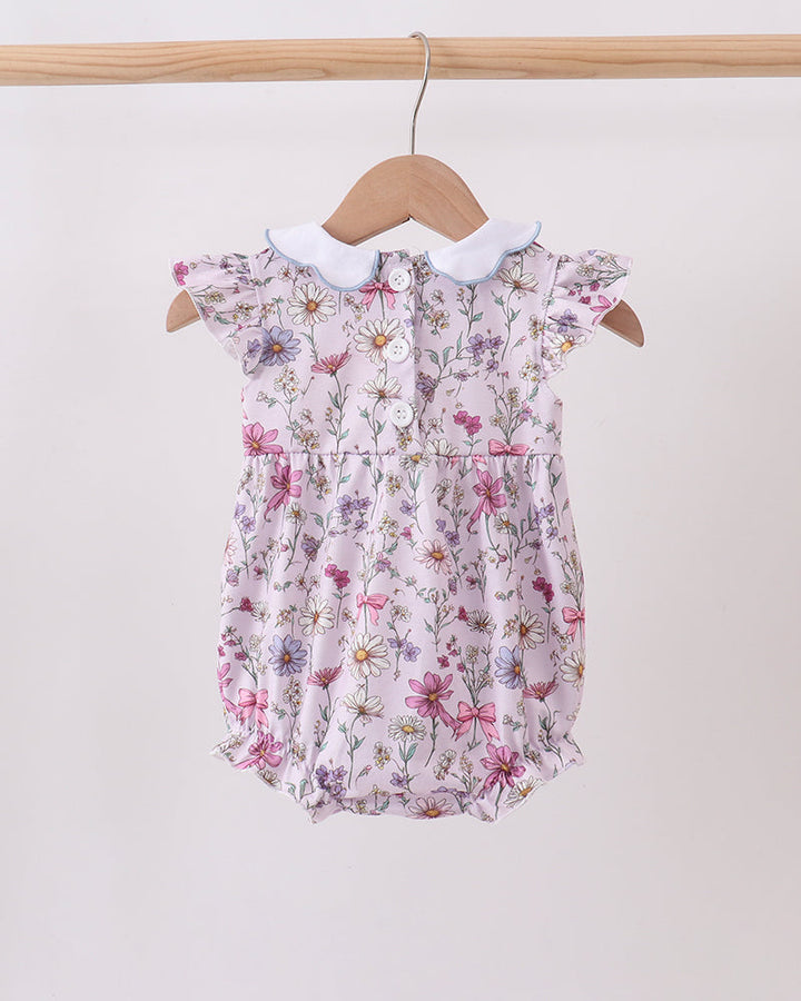 Floral baby romper on a hanger against a white background
