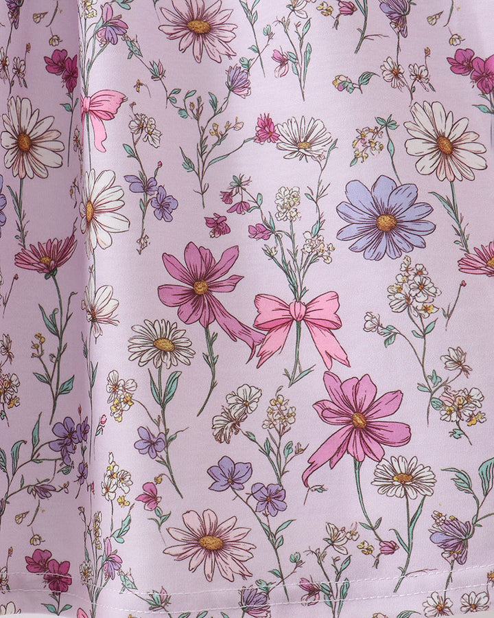 Floral patterned fabric with pink flowers and bows on a light purple background