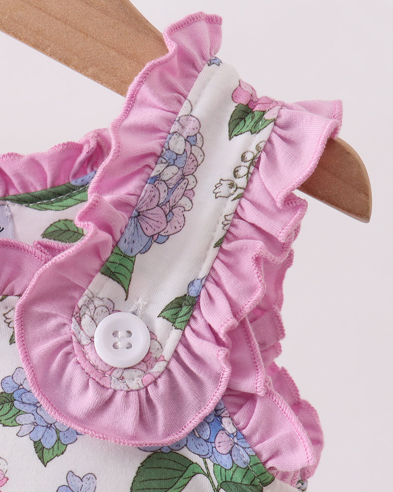 Floral-patterned fabric with pink ruffled trim on a wooden hanger.
