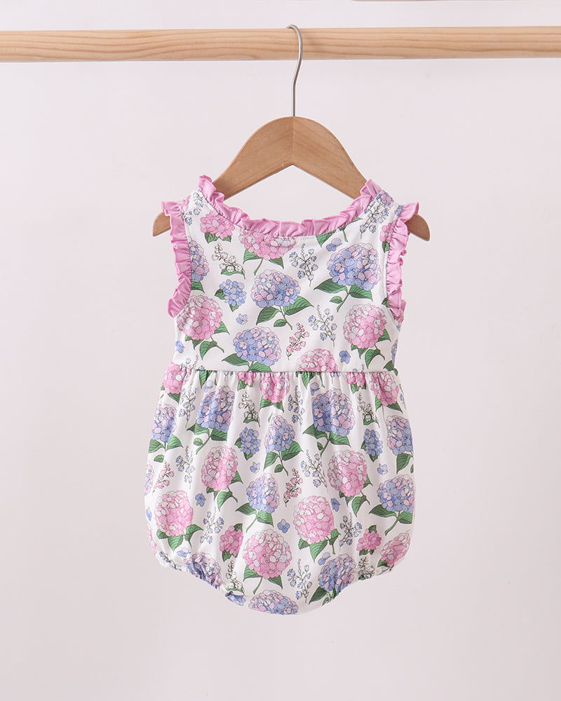 Floral baby romper on a wooden hanger against a light background