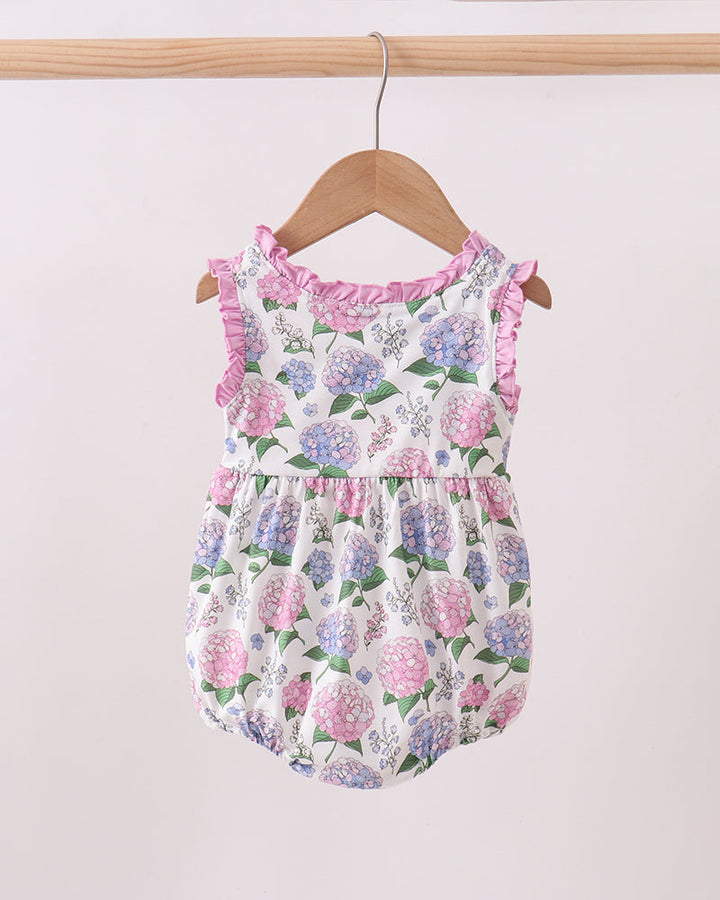 Floral baby romper on a wooden hanger against a light background