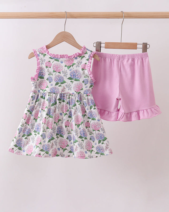 Floral dress and pink shorts on hangers against a white background
