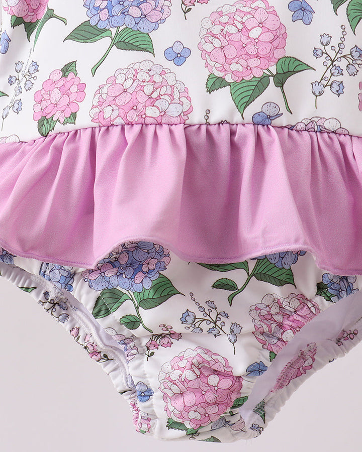 Floral-patterned swimsuit with pink ruffle on a light gray background