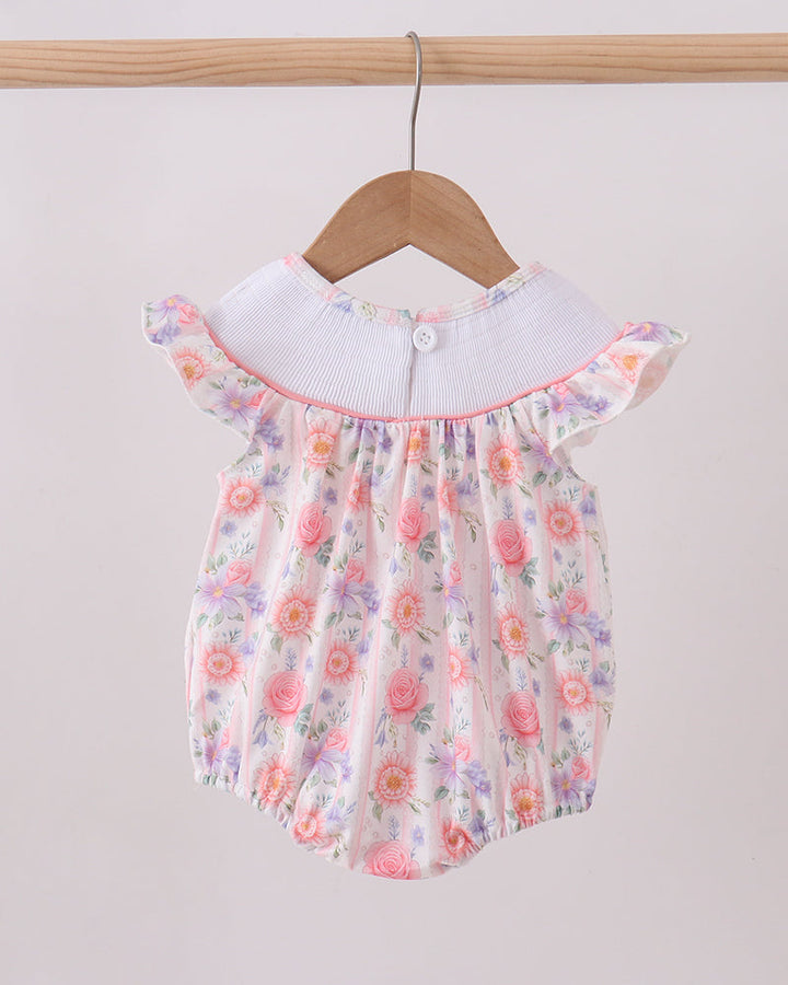 Floral baby romper with white collar on a wooden hanger against a light gray background