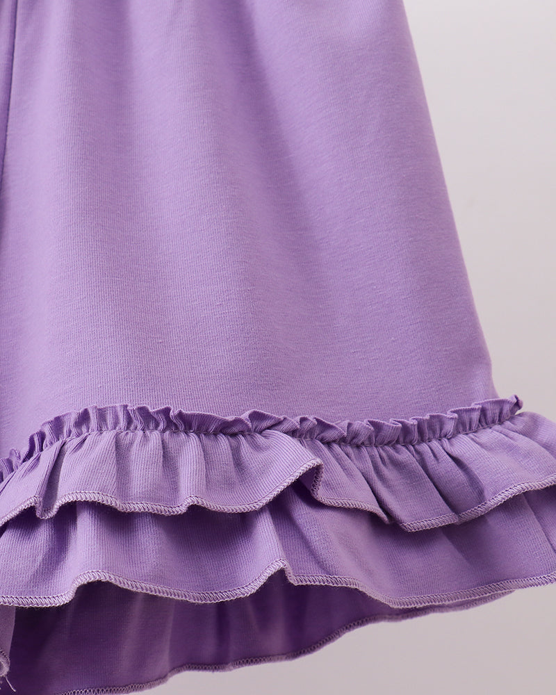 Close-up of a purple dress with ruffled hem on a light gray background