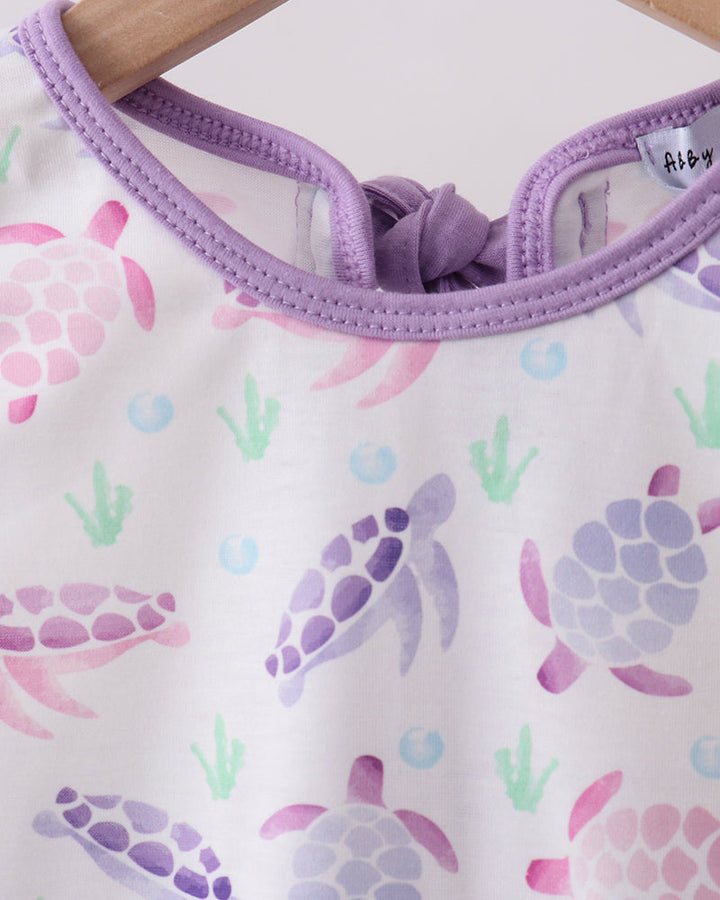 Baby outfit with turtle pattern and purple trim on a white background