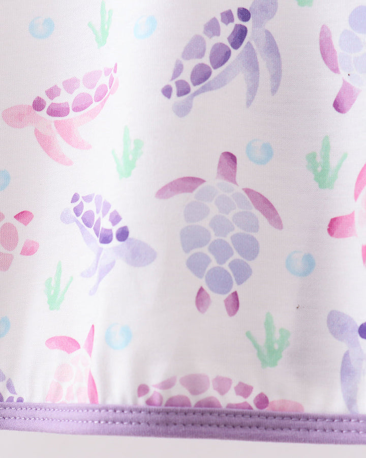 Close-up of a product with turtle pattern and purple zipper on a light background