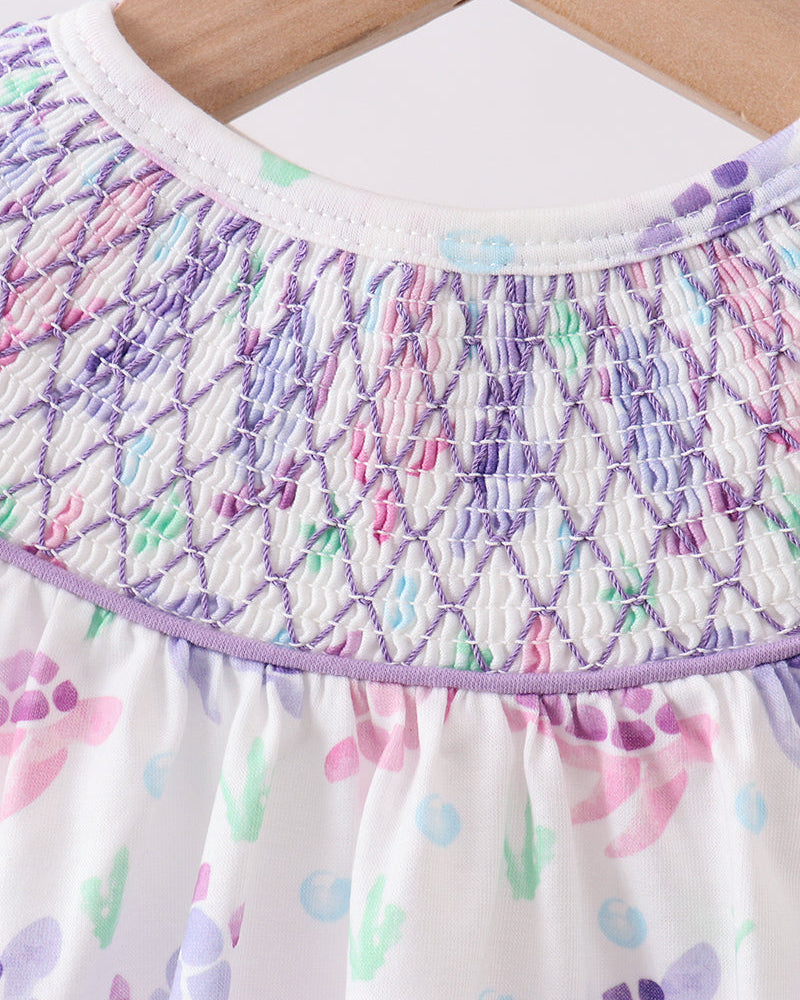Close-up of a dress with floral pattern and smocked neckline.