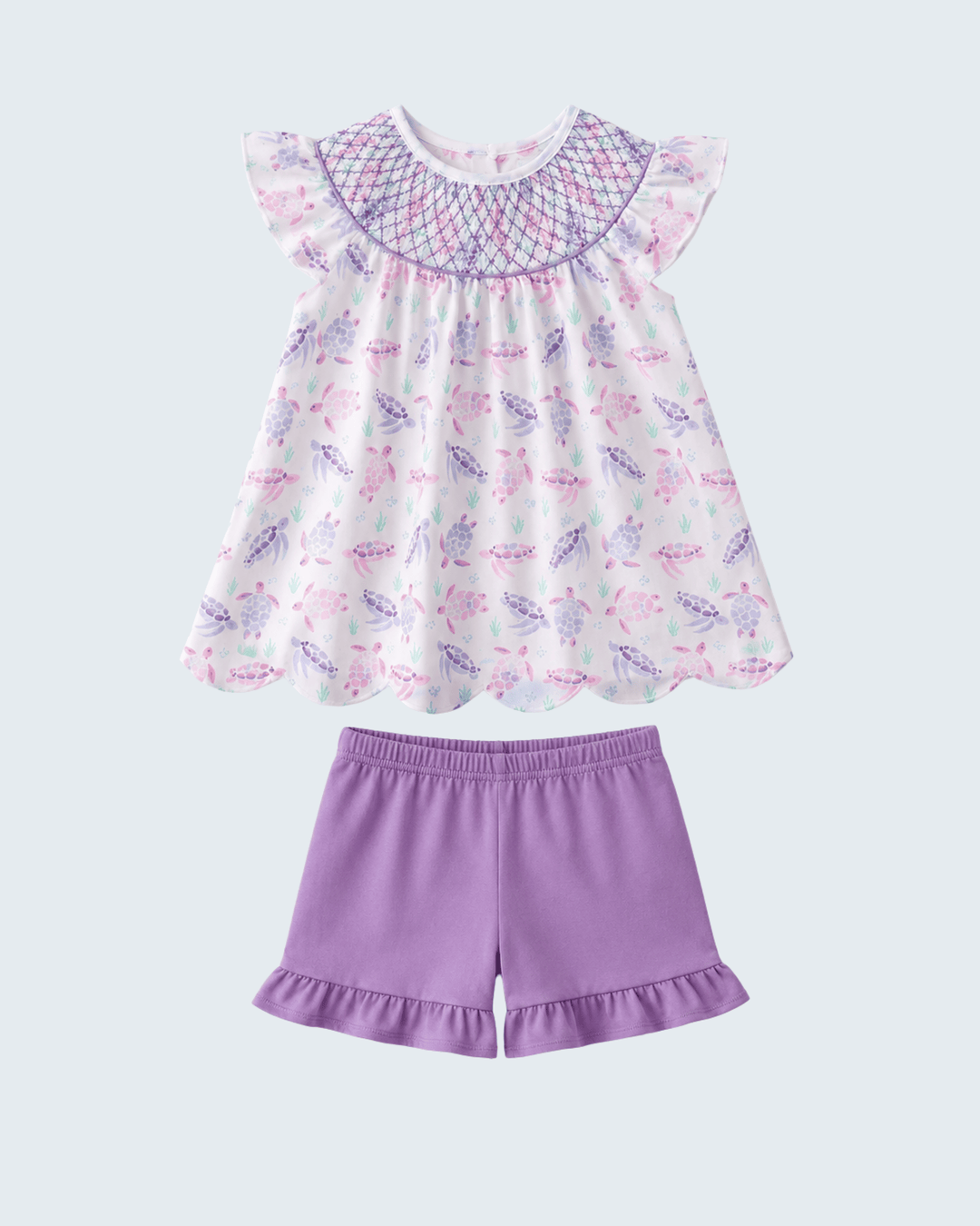 Children's outfit with a patterned top and purple shorts on a white background