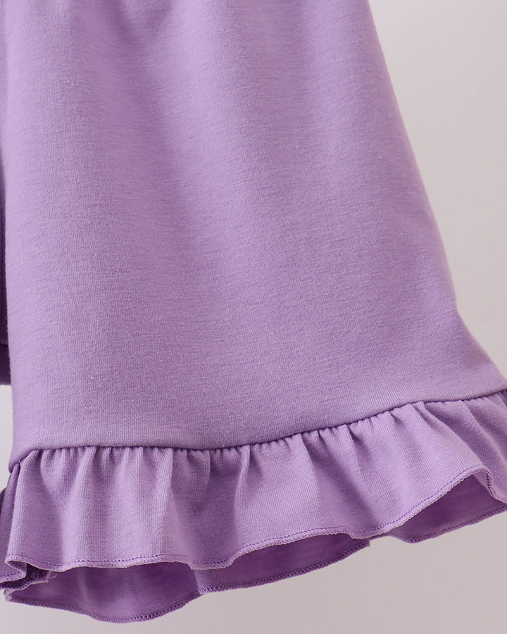 Close-up of a purple skirt with ruffled hem on a light gray background