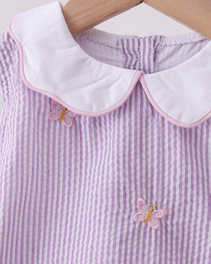 Purple and white striped dress with butterfly details on a wooden hanger