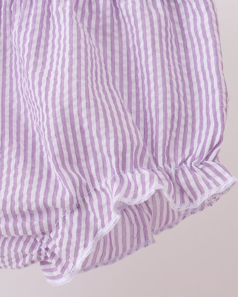 Purple and white striped fabric with ruffled edge on a light gray background