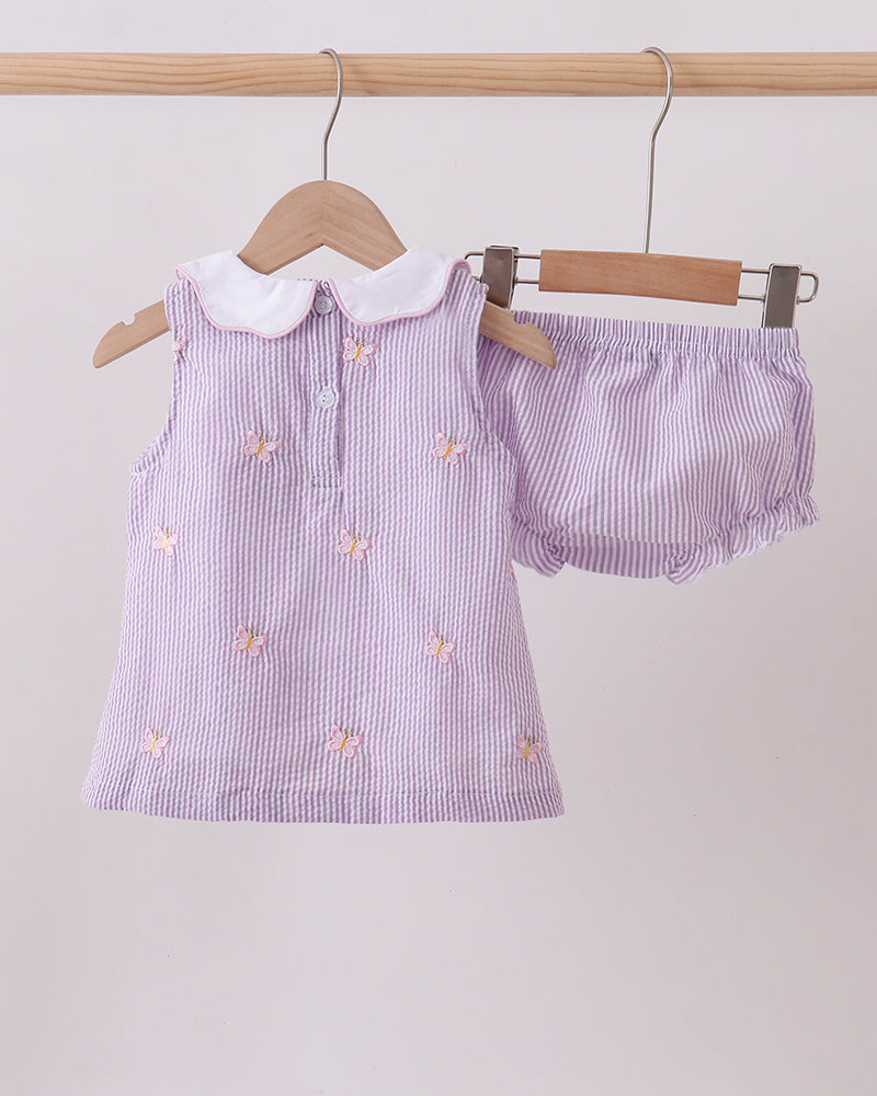 Purple striped dress with white collar and matching bloomers on hangers against a light gray background