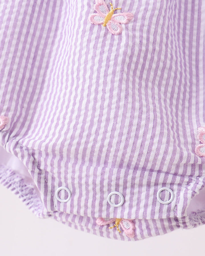 Purple and white striped baby romper with pink butterfly accents on a light gray background