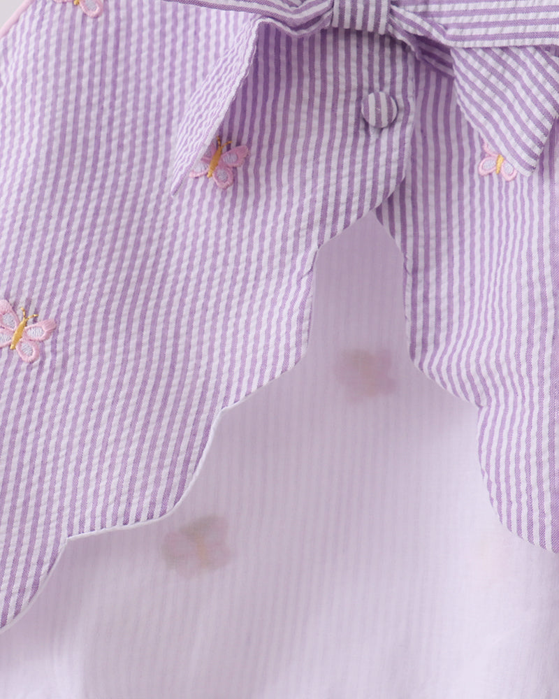 Close-up of a purple and white checkered shirt with butterfly designs on a light gray background