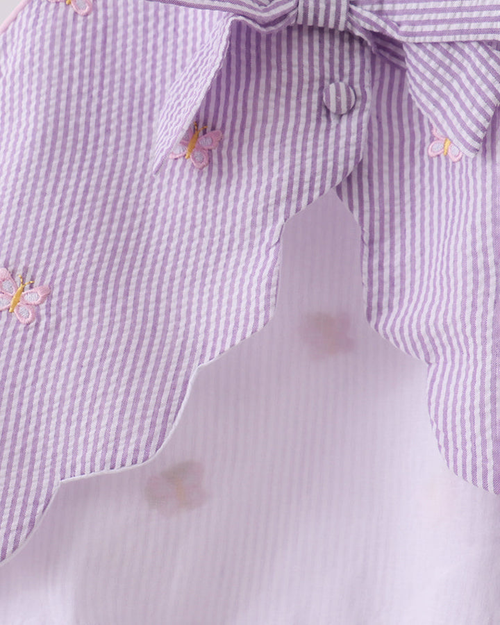 Close-up of a purple and white checkered shirt with butterfly designs on a light gray background
