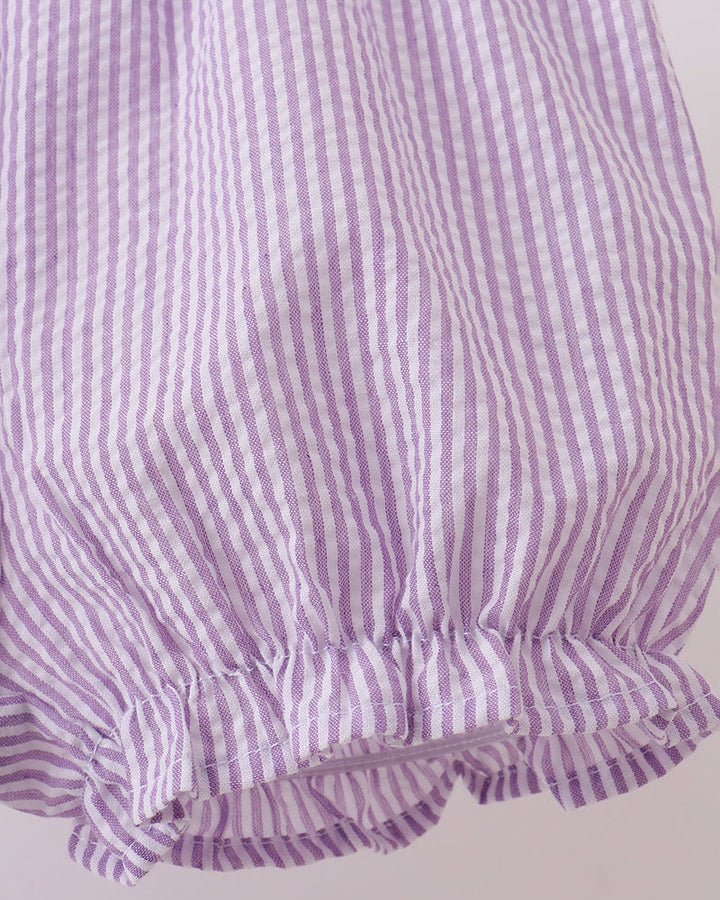Close-up of a purple and white striped fabric with ruffled edge on a light gray background