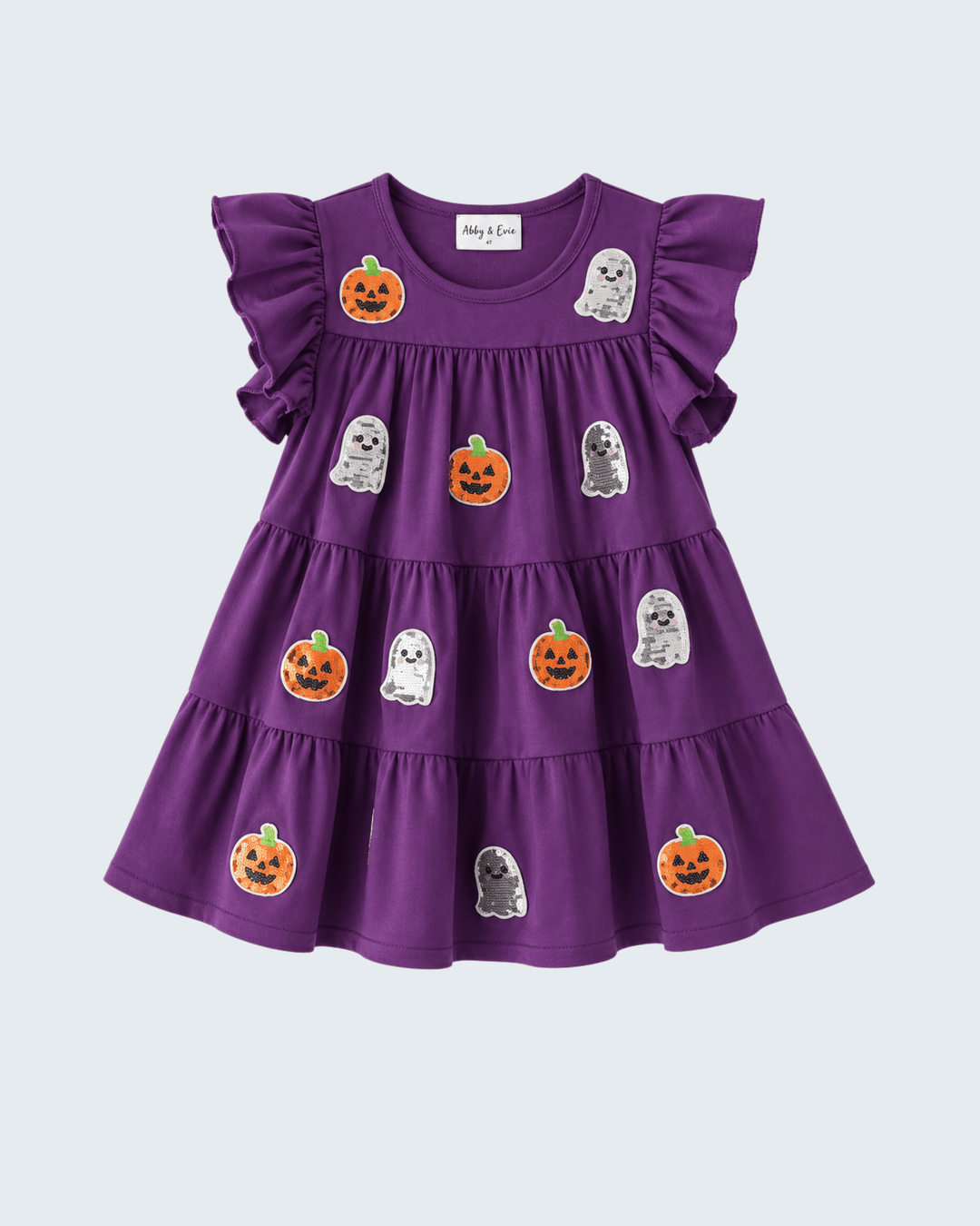 A purple tiered baby dress with ruffled sleeves, decorated with embroidered orange jack-o'-lanterns and white ghosts, shown on a light gray background.
